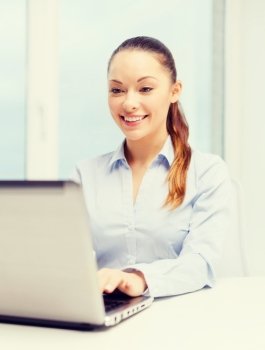 business, technology, internet and office concept - smiling businesswoman with laptop in office