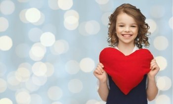 love, charity, holidays, children and people concept - smiling little school girl with red heart over lights background