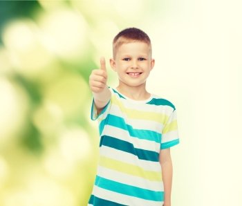 happiness, childhood, ecology and people concept - smiling little boy in casual clothes showing thumbs up over green background