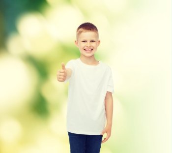 advertising, ecology, gesture, people and childhood concept - smiling boy in white blank t-shirt showing thumbs up over green background