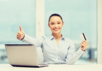 business, investing and technology concept - businesswoman with laptop and credit card in office showing thumbs up