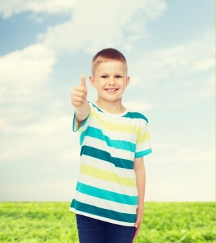 happiness, childhood, environment and people concept - smiling little boy in casual clothes showing thumbs up over natural background