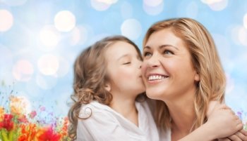 people, happiness, love, family and motherhood concept - happy daughter hugging and kissing her mother over blue lights and poppy field background