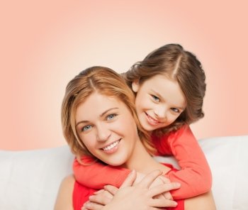 people, love, holidays, family and motherhood concept - happy mother and daughter hugging over pink background
