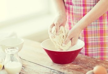cooking and home concept - close up of female hands kneading dough at home