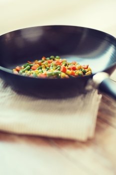 cooking, food and home concept - close up of wok pan with vegetables