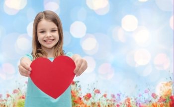 love, charity, holidays, children and people concept - smiling little girl with red heart over blue lights and poppy field background