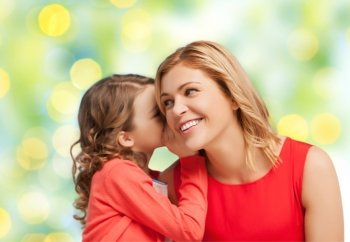 people, trust, love, family and motherhood concept - happy daughter whispering gossip to her mother over green lights background