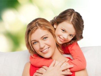 people, love, holidays, family and motherhood concept - happy mother and daughter hugging over green background