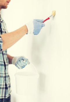 interior design and home renovation concept - man hands with paintbrush and paint pot