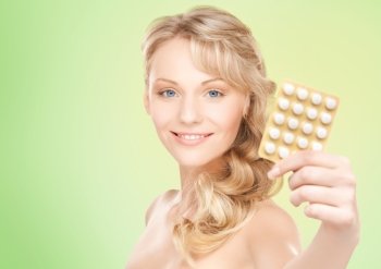 people, beauty, healthcare and medicine concept - happy young woman holding package of pills over green background