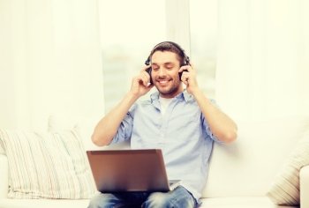 technology, home, music and lifestyle concept - smiling man with laptop and headphones at home