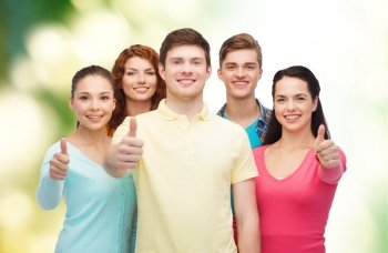 friendship, ecology, gesture and people concept - group of smiling teenagers showing thumbs up over green background