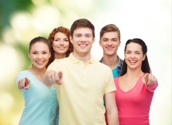 friendship, ecology, gesture and people concept - group of smiling teenagers pointing finger on you over green background