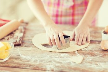 cooking and home concept - close up of female hands making cookies from fresh dough at home
