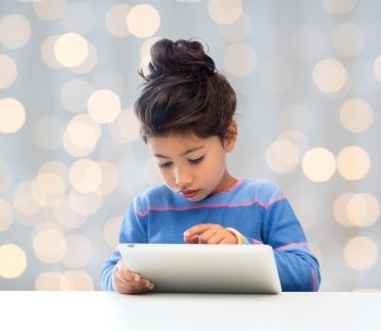 education, technology and children concept - little student girl with tablet pc over holidays lights background