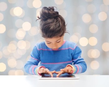 education, technology and children concept - little student girl with tablet pc over holidays lights background