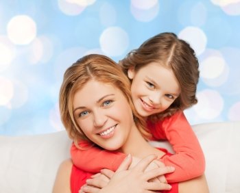 people, happiness, love, family and motherhood concept - happy mother and daughter hugging over blue lights background
