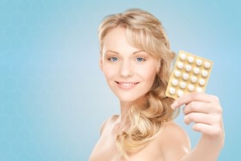 people, beauty, healthcare and medicine concept - happy young woman holding package of pills over blue background