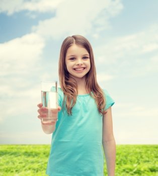 health and beauty concept - smiling little girl giving glass of water