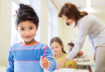 education, elementary school and children concept - happy little student girl with pen over classroom and teacher background