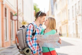 travel, vacation, love and friendship concept - smiling couple with map and backpack in city
