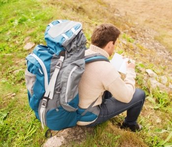 adventure, travel, tourism, hike and people concept - man with backpack sitting on ground from back