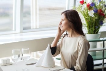 people, women, business and lifestyle concept - happy woman sitting at table and calling on smart phone in restaurant