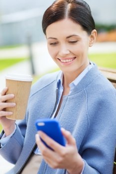 business and people concept - young smiling woman with smartphone sitting on bench and drinking coffee in city. smiling woman with coffee and smartphone