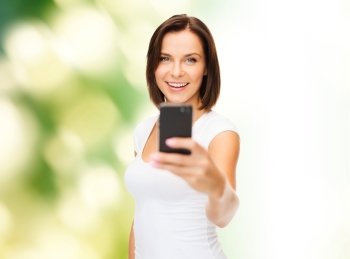 people, summer and technology concept - young woman taking selfie with smartphone over green natural background
