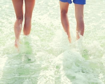 sea, summer vacation, holidays and people concept - close up of couple running into water