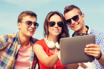 friendship, leisure, summer, technology and people concept - group of smiling friends with tablet pc computer and headphones sitting outdoors