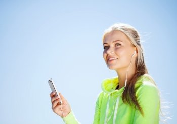 sport and lifestyle concept - woman doing sports and listening to music outdoors. woman listening to music outdoors