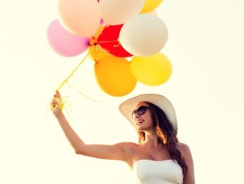 happiness, summer, holidays and people concept - smiling young woman wearing sunglasses with balloons outdoors