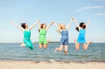 summer holidays and vacation concept - smiling girls jumping on the beach. smiling girls jumping on the beach