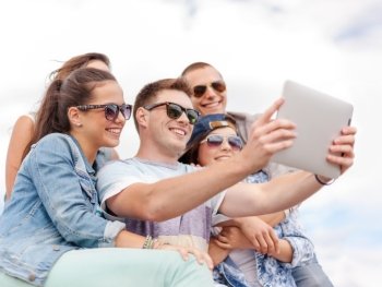 summer holidays, teenage and technology concept - group of smiling teenagers in sunglasses taking picture with tablet pc