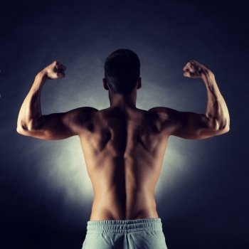 sport, bodybuilding, strength and people concept - young man showing biceps over gray background from back