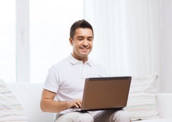 technology, people lifestyle and networking concept - happy man working with laptop computer at home