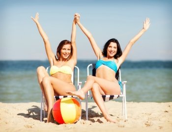 summer holidays and vacation - girls in bikinis sunbathing on the beach chairs