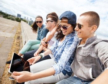 summer holidays, teenage and technology concept - group of teenagers looking at tablet pc