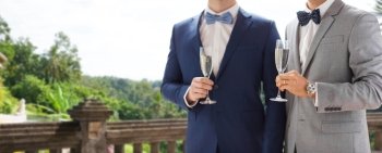 people, celebration, homosexuality, same-sex marriage and love concept - close up of happy married male gay couple drinking sparkling wine from glasses on wedding over balcony and nature background