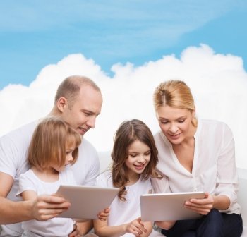 family, technology and people - smiling mother, father and little girls with tablet pc computers over blue sky and white cloud background