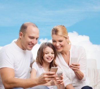 family, technology and people concept - smiling mother, father and little girl with smartphones over blue sky and white cloud background