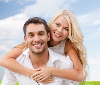 summer holiday, vacation, dating and love concept - happy couple having fun over blue sky and grass background
