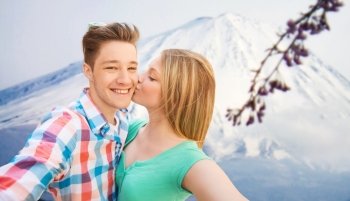 travel, vacation, technology, people and love concept - smiling couple with smartphone over japan mountains background