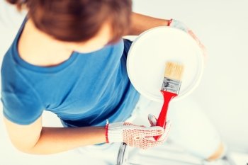 interior design and home renovation concept - woman with paintbrush and paint pot. woman with paintbrush and paint pot