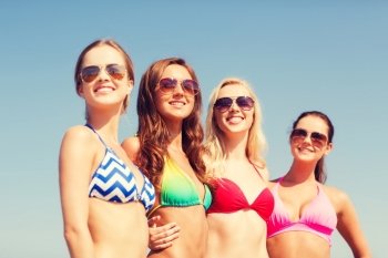 summer vacation, holidays, travel and people concept- group of smiling young women on beach over blue sky background