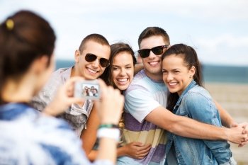 summer holidays and technology concept - group of teenagers taking photo outside. teenagers taking photo outside