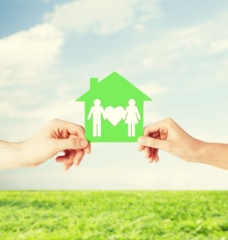 real estate and family home concept - isolated picture of male and female hands holding green paper house with family. hands holding green house with family