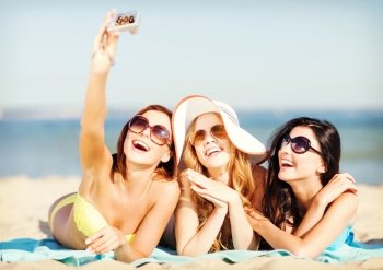 summer holidays, vacation and beach concept - girls in bikinis taking self photo on the beach